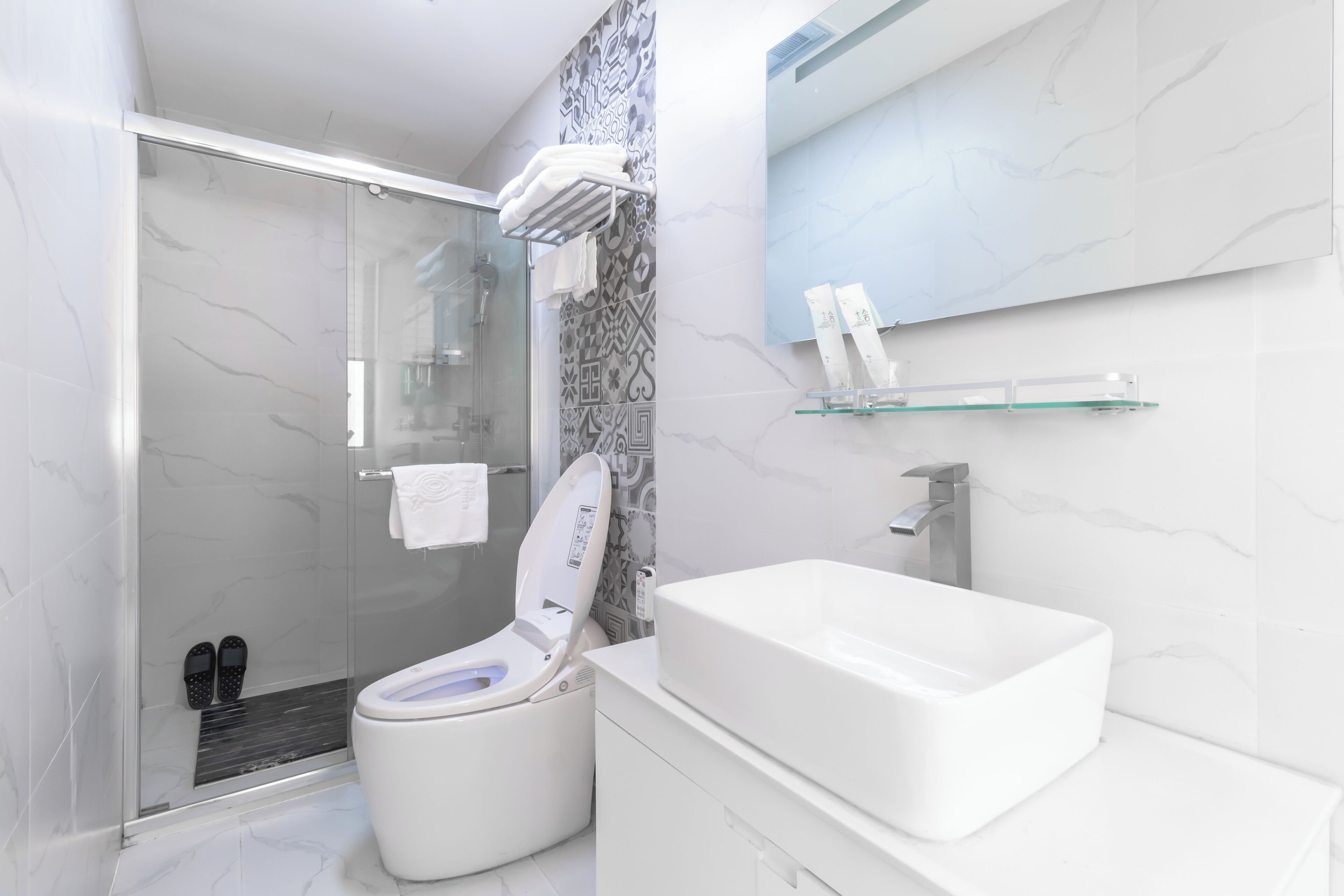 A modern bathroom with a glass-enclosed shower, a white toilet, and a rectangular sink.