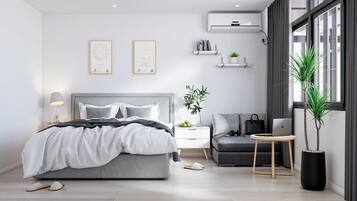 A modern bedroom with a bed, bedside table, chair, and a desk with a laptop.