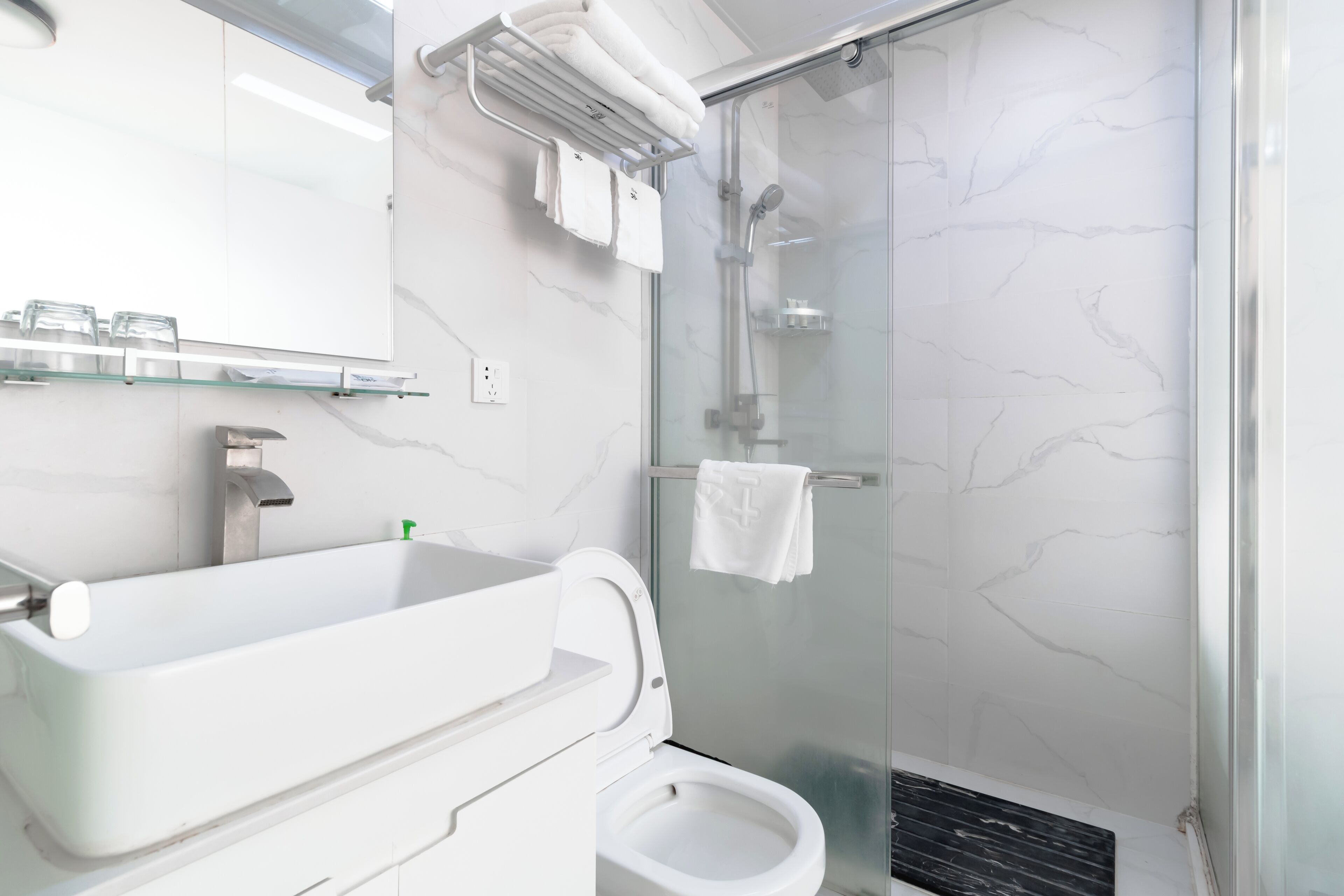 A modern bathroom with a glass-enclosed shower, a white sink, and a toilet.