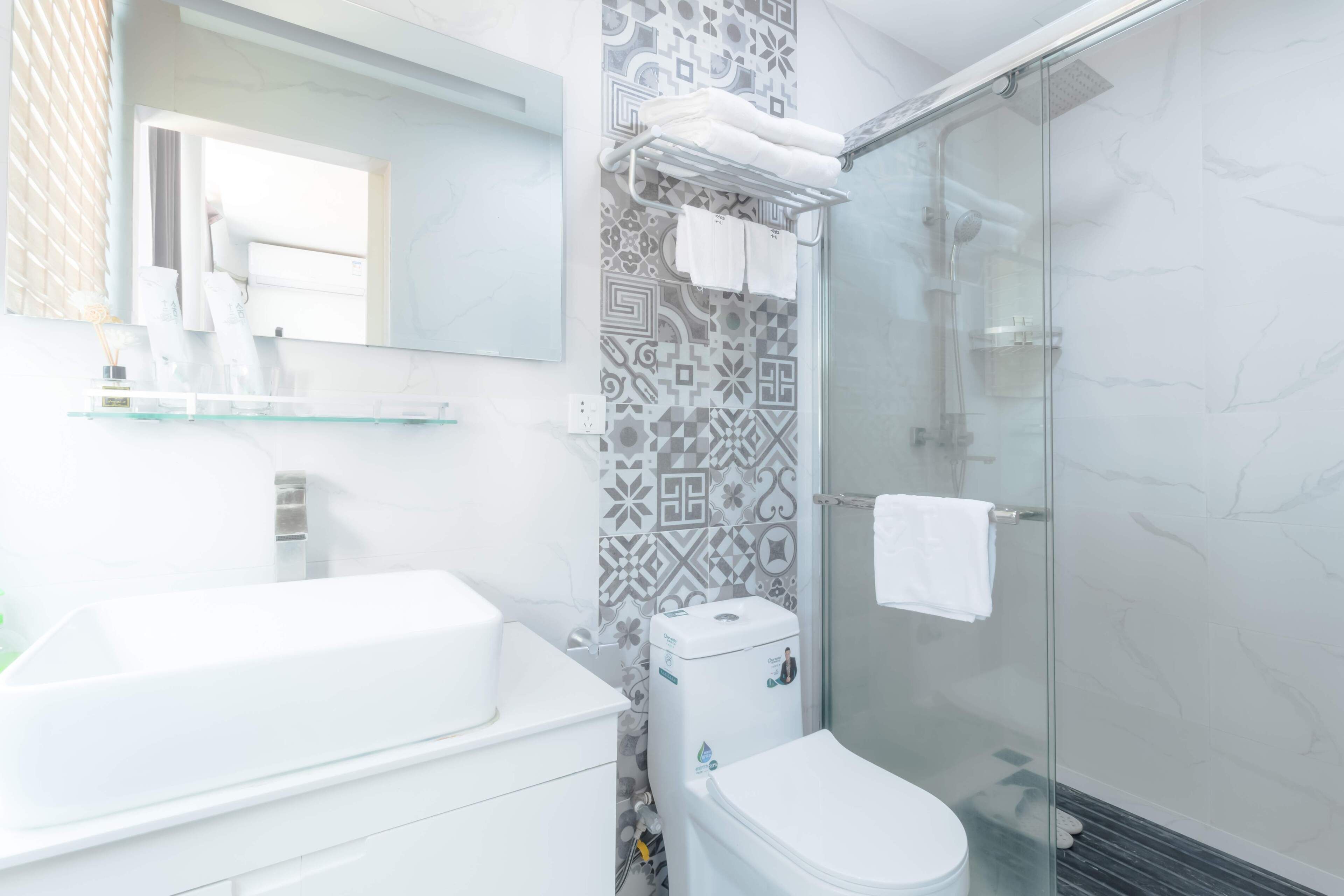 Ein modernes Badezimmer mit einer Duschkabine aus Glas, einer weißen Toilette und einem großen weißen Waschbecken.