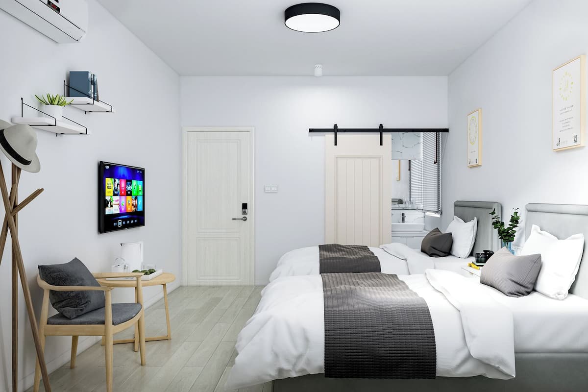 Ein modernes Schlafzimmer mit Bett, Nachttisch, Sessel, Fernseher und einem Badezimmer mit Spiegel und Waschbecken.