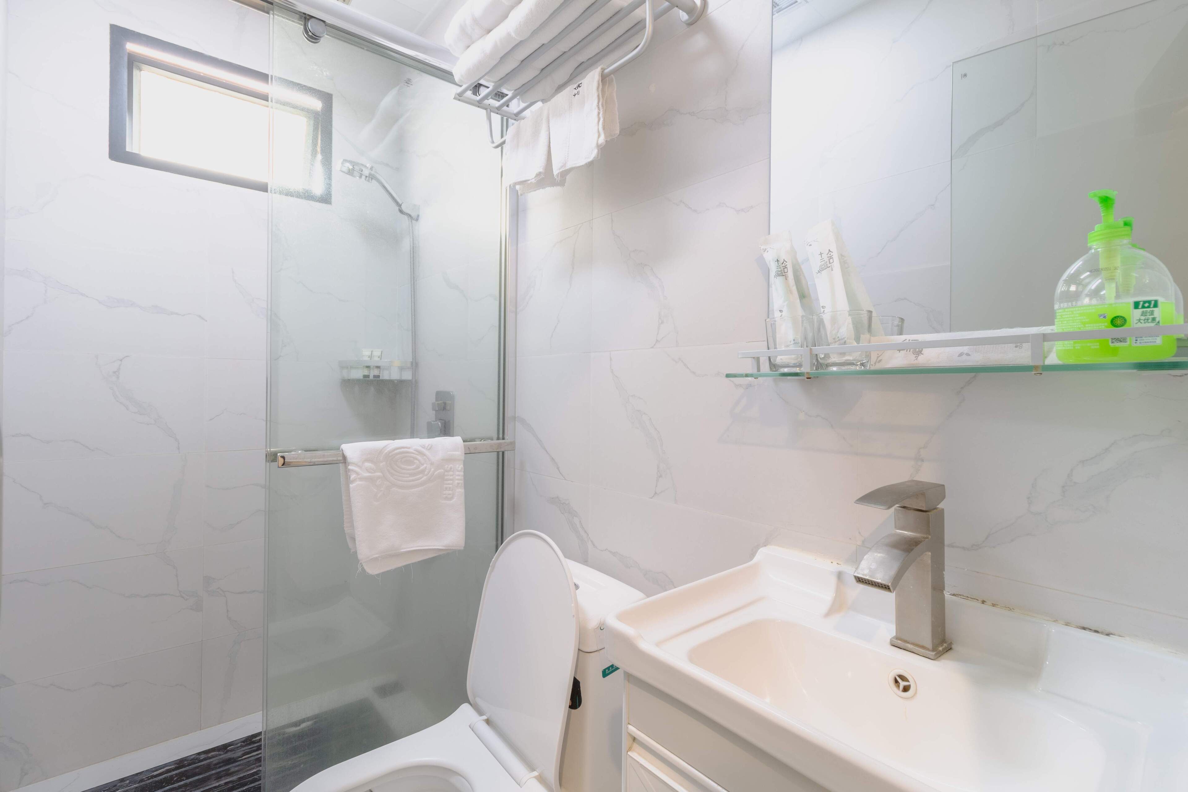 A modern bathroom with a glass-enclosed shower, a white toilet, a sink with a chrome faucet, and a mirror above the sink.