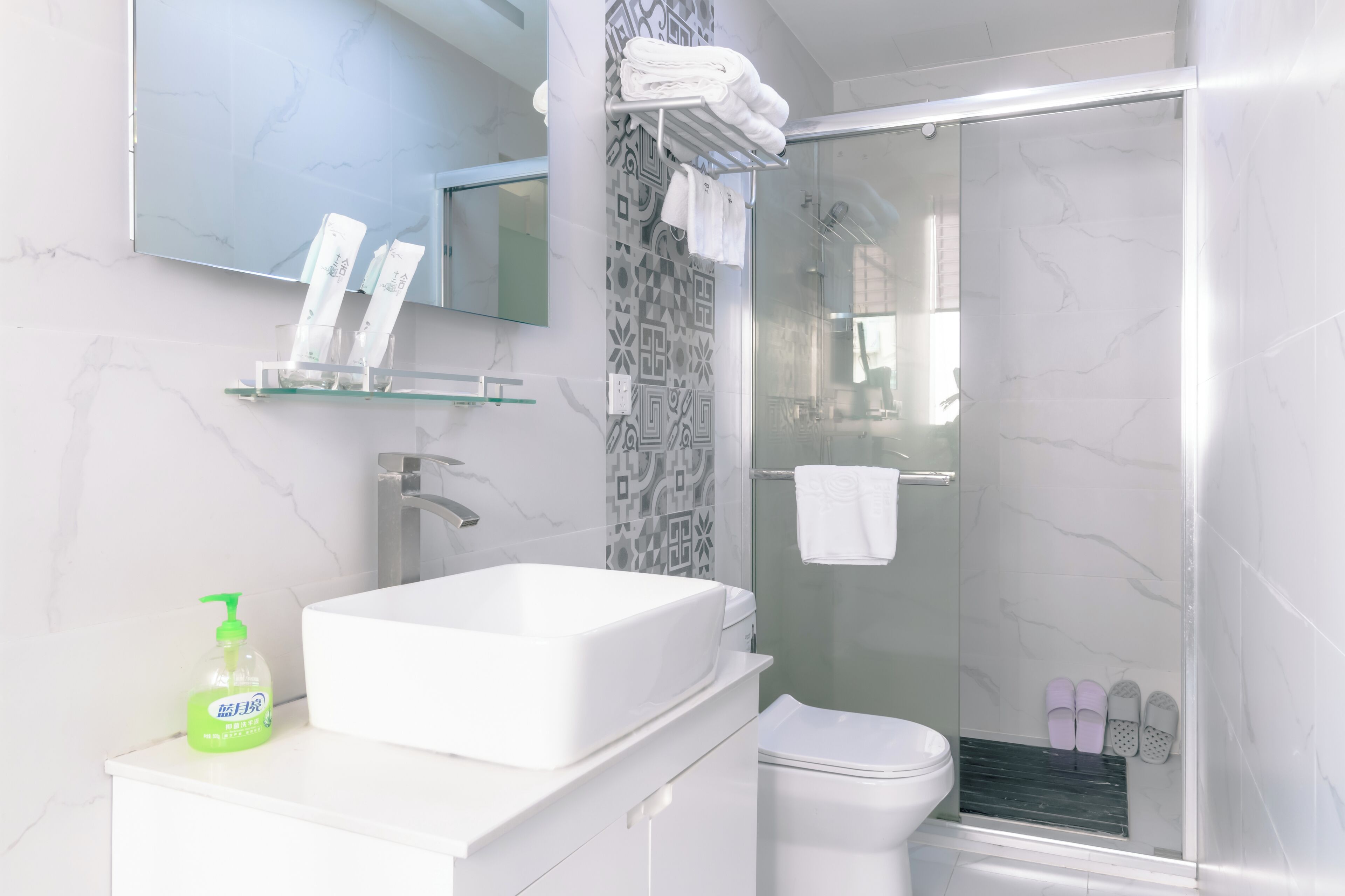 Un baño moderno con un lavamanos grande de color blanco, una cabina de ducha de vidrio y un inodoro.