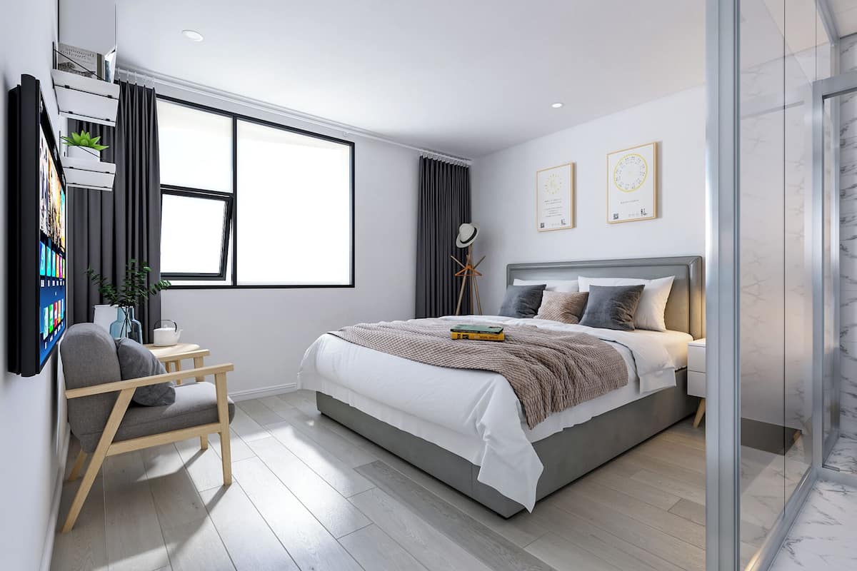 Ein modernes Schlafzimmer mit einem großen Bett, einem Schreibtisch mit Stuhl, einem an der Wand montierten Fernseher und einem Fenster mit Vorhängen.