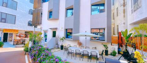 Un patio con mobiliario exterior, un restaurante y un edificio de diseño moderno.