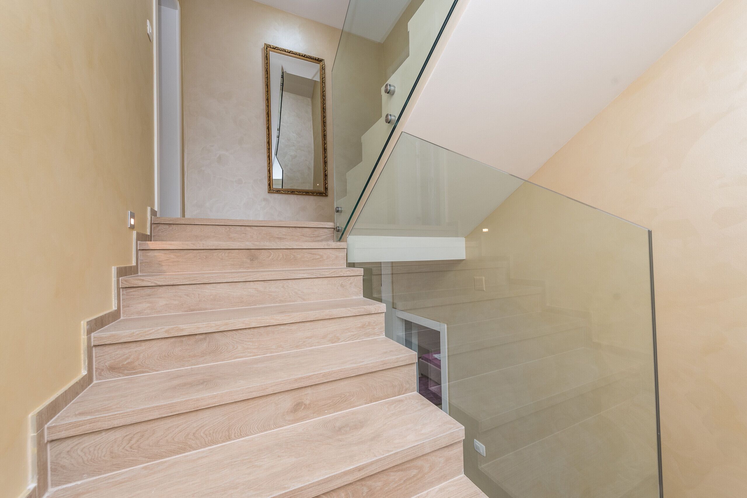 A staircase with wooden steps and a glass railing.