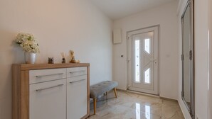 Un pasillo con un armario blanco, un banco y una puerta que da a otra habitación.