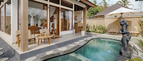 Una casa moderna con piscina, mobiliario exterior y una estatua.