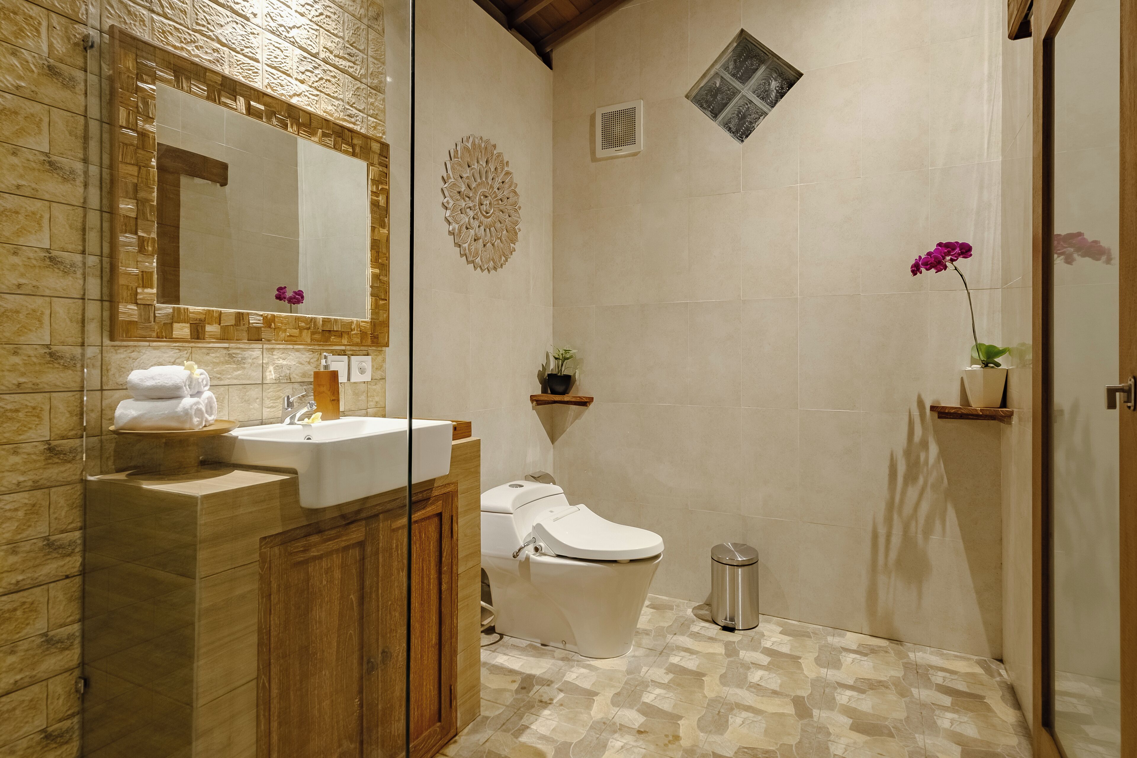 Un baño con tocador de madera, lavamanos, inodoro y zona de ducha.