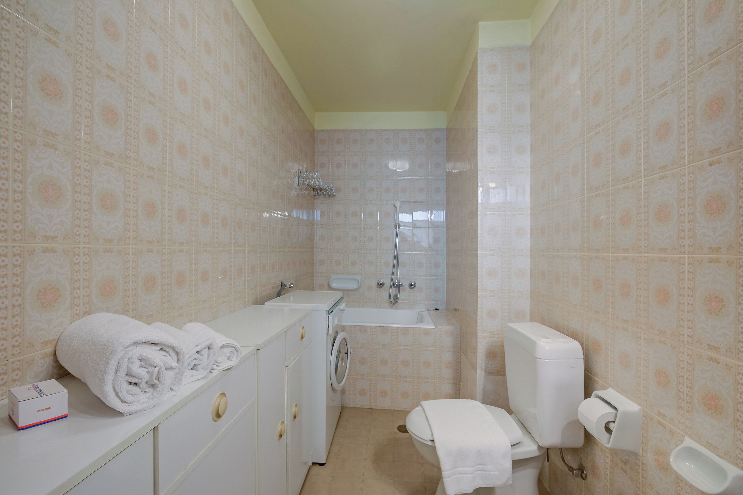 Ein kleines Badezimmer mit Waschmaschine, Toilette und Waschbecken.