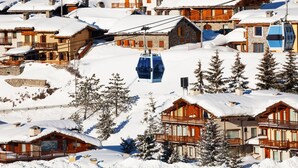 Un villaggio montano innevato con edifici in legno e una seggiovia.
