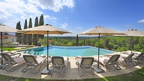 A poolside area with lounge chairs and umbrellas, overlooking a swimming pool and a scenic landscape. - Amazing Panoramic Villa La Poggiola (Arezzo)