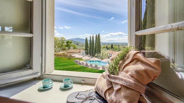 A window with a view of a pool, greenery, and distant mountains. - Amazing Panoramic Villa La Poggiola (Arezzo)
