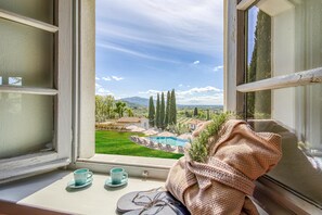 A window with a view of a pool, greenery, and distant mountains. - Amazing Panoramic Villa La Poggiola (Arezzo)