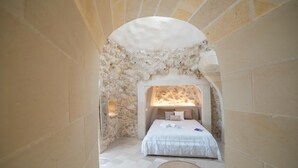 A bedroom with a stone archway, a bed with white linens, and a small rug on the floor. - Lis ria Villa Delle Meraviglie With Pool (Castrignano de' Greci)