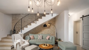Un salon moderne avec un escalier à volutes, un canapé vert, une table basse ronde et un design minimaliste.