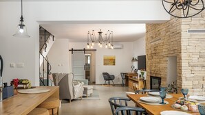 Une cuisine moderne avec un îlot central en bois, des tabourets de bar et un coin repas doté d’une table en bois, préparée pour accueillir quatre personnes.