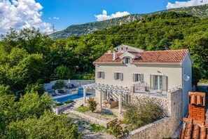 A two-story house with a swimming pool, outdoor seating, and a stone wall. - Nature Villa Frangipane With Pool (Vinodol)