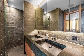 Ein modernes Badezimmer mit einem großen Waschbecken, zwei Wasserhähnen und einer Duschkabine.