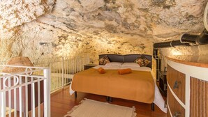 Un dormitorio con una cama, una mesita de noche, una lámpara y un armario de madera.
