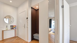 A modern hotel room with a wooden floor, a console table with a mirror, a small bench, and a wardrobe. - Novos Diamond in Lugano (Lugano)