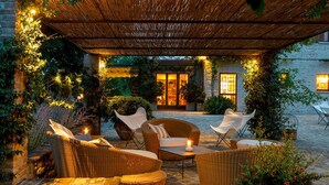 An outdoor patio area with wicker furniture, a stone floor, and a covered section with a bamboo roof. - Casa Eugenia 8 Emma Villas (Pesaro)
