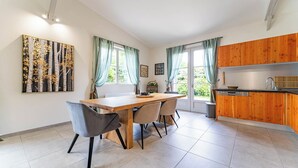 Una cuina moderna amb armaris de fusta, una taula de dinar amb cadires i una finestra amb cortines.