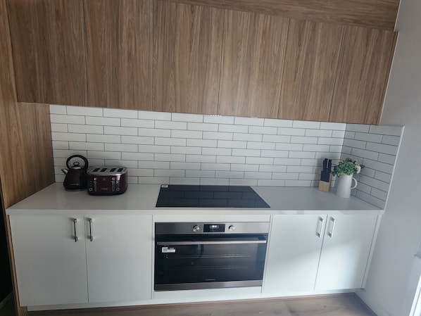 A kitchen with white cabinets, a black oven, a kettle, and a toaster.