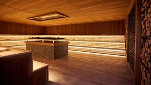 Una sauna con bancos de madera y una plataforma central de piedra.