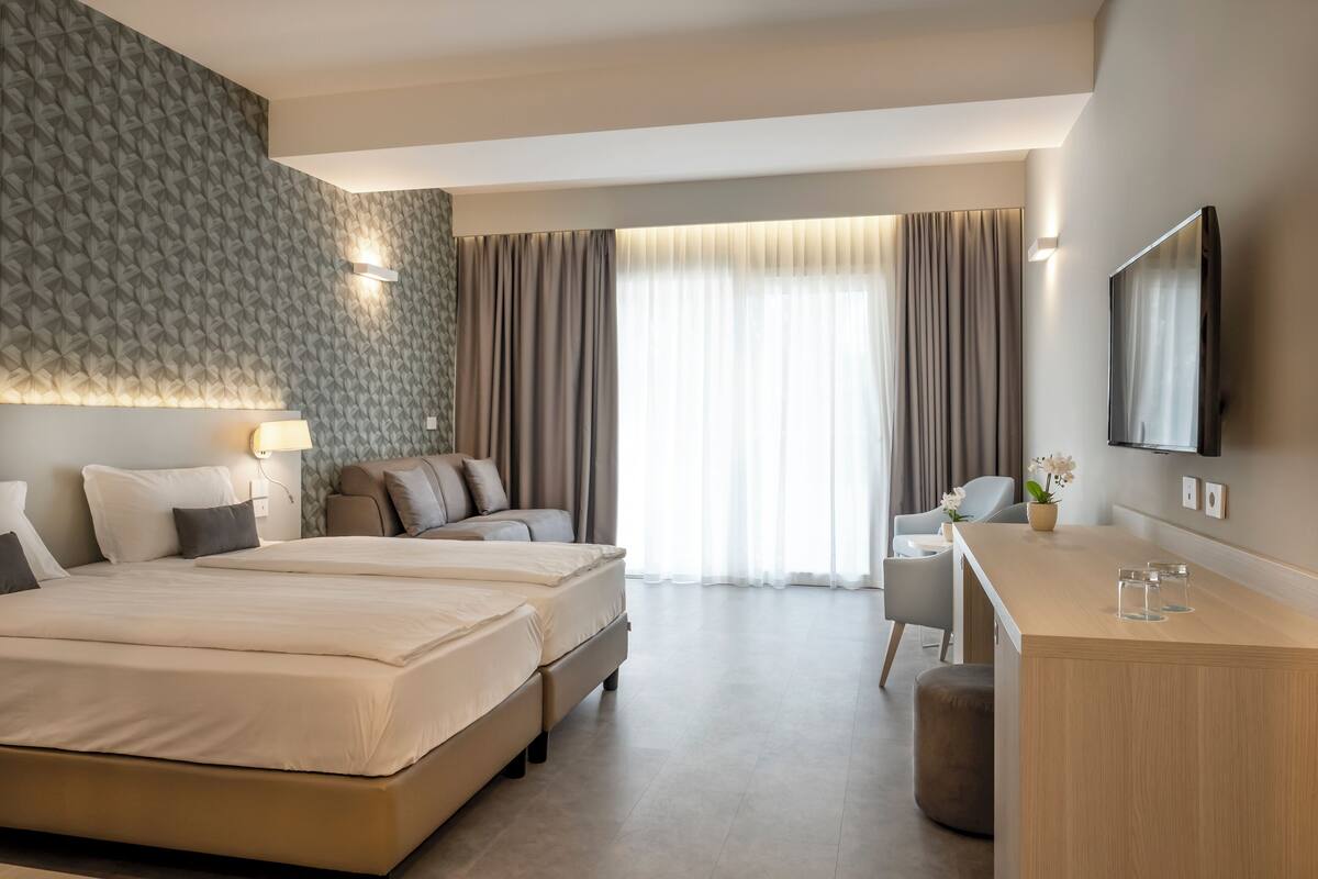 A modern hotel room with a large bed, a desk, and a TV.