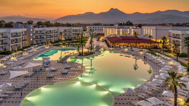 Un resort con una amplia piscina, varias zonas de descanso y un restaurante.
