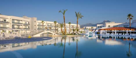 Un resort con una piscina grande, palmeras y edificios modernos.