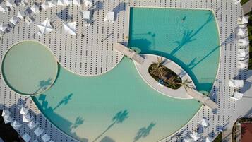 Relax by the large, circular pool surrounded by lounge chairs and umbrellas.