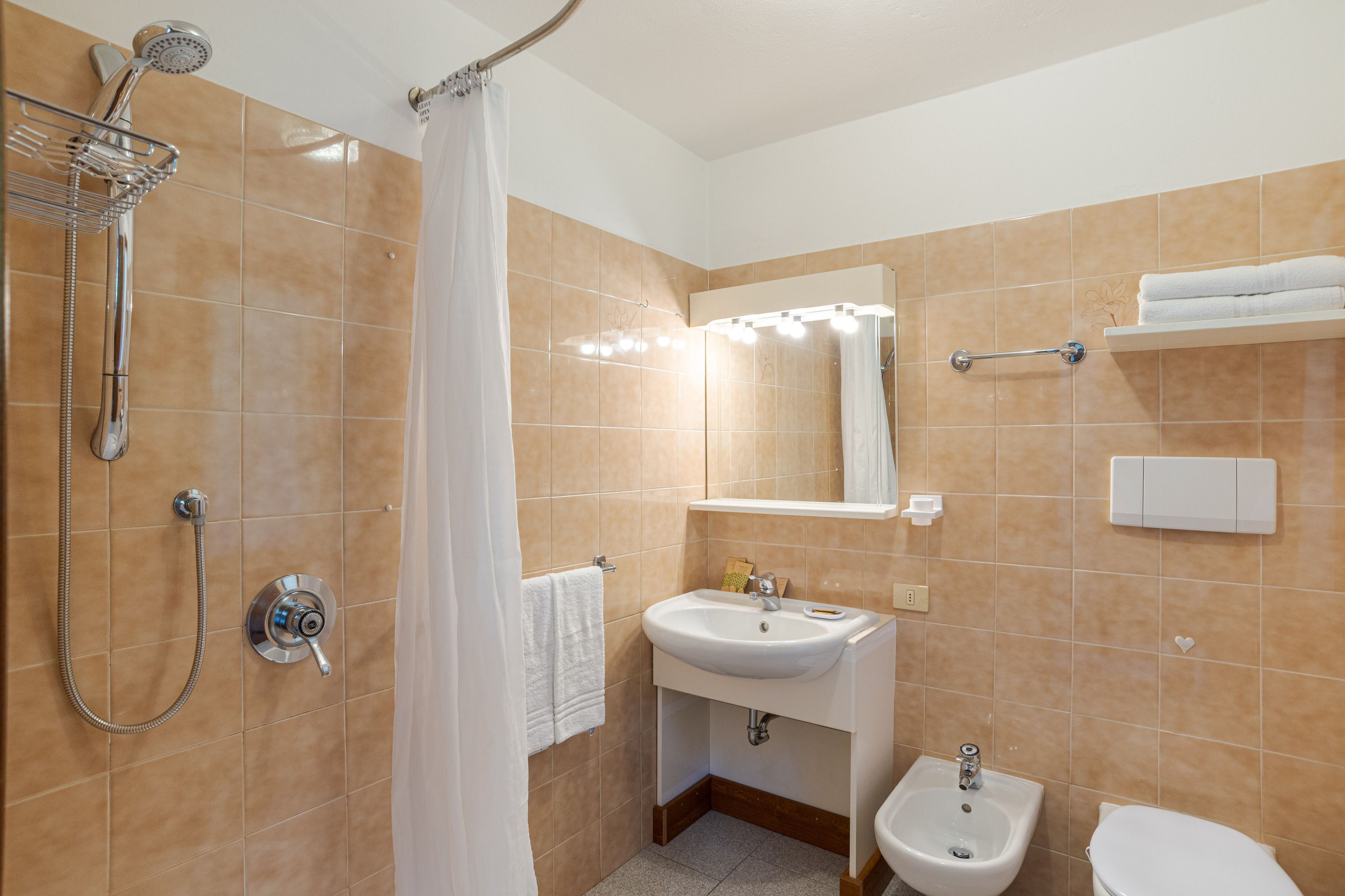 Un baño con ducha, lavamanos, bidé e inodoro.