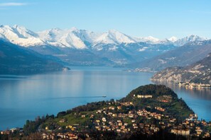 A panoramic view of a lake surrounded by snow-capped mountains and a small town with houses and buildings along the shore. - Residenza Menaggio - Mimosa (Menaggio)