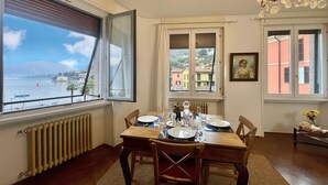 Un comedor con una mesa dispuesta para cuatro, vista al mar y edificios, y un candelabro.
