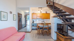 A modern kitchen with wooden cabinets, a dining table, and a built-in TV. - CO RI Appartamenti 1 (Menaggio)