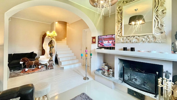 A living room with a fireplace, a staircase, and a large mirror. - Villa Alice in Menaggio (Menaggio)