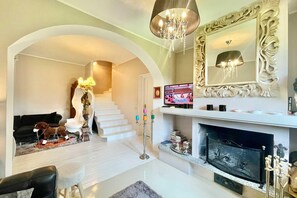 Ein Wohnzimmer mit Kamin, Treppe und einem großen Spiegel.