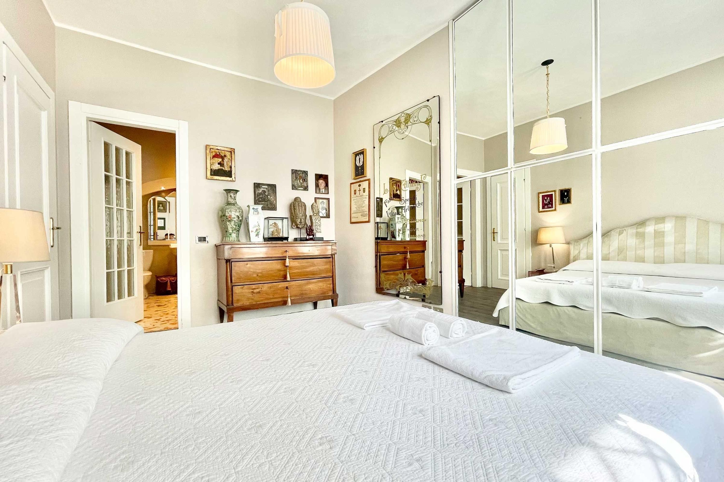 A spacious bedroom with a large bed, a wooden dresser, and a mirror.