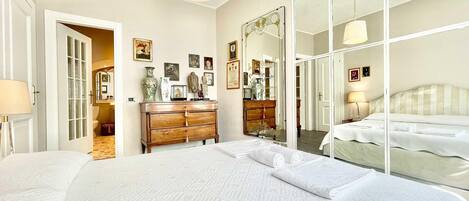 A spacious bedroom with a large bed, a wooden dresser, and a mirror.