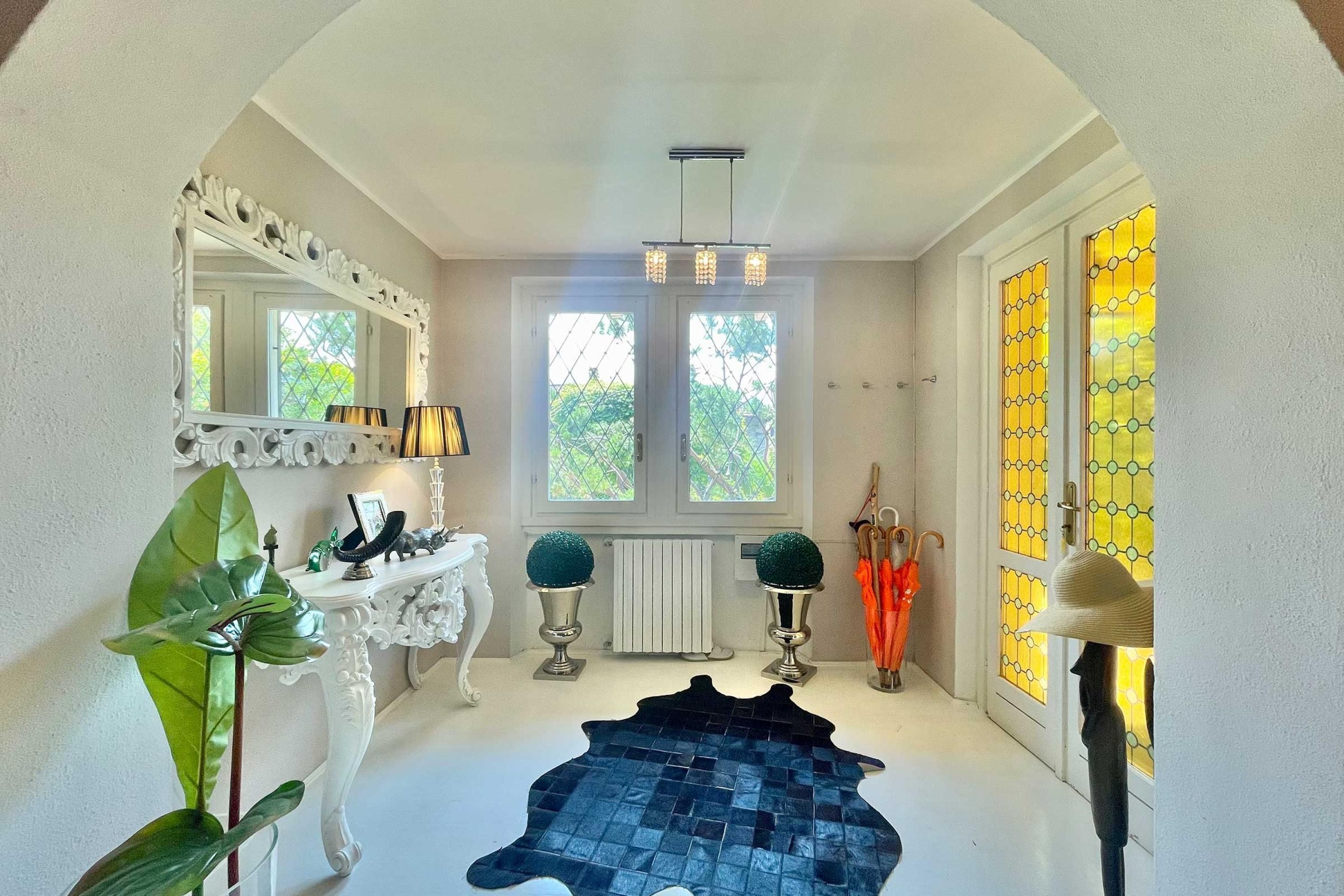 A hallway with a white console table, a mirror, a black rug, and a radiator.