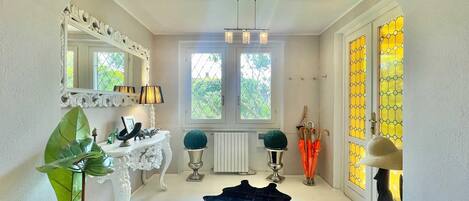 A hallway with a white console table, a mirror, a black rug, and a radiator.
