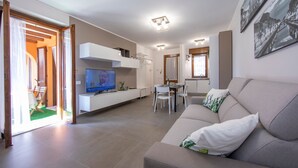 A modern living room with a sofa, TV, dining table, and chairs. - Menaggio Palphi in Menaggio (Menaggio)