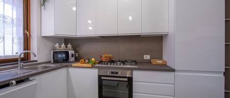 A modern kitchen with white cabinets, a built-in oven, a microwave, and a gas stove.