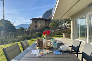 A table set outdoors with a magazine, a candle, and a vase with red flowers. - Modern House Apartment 1 (Menaggio)