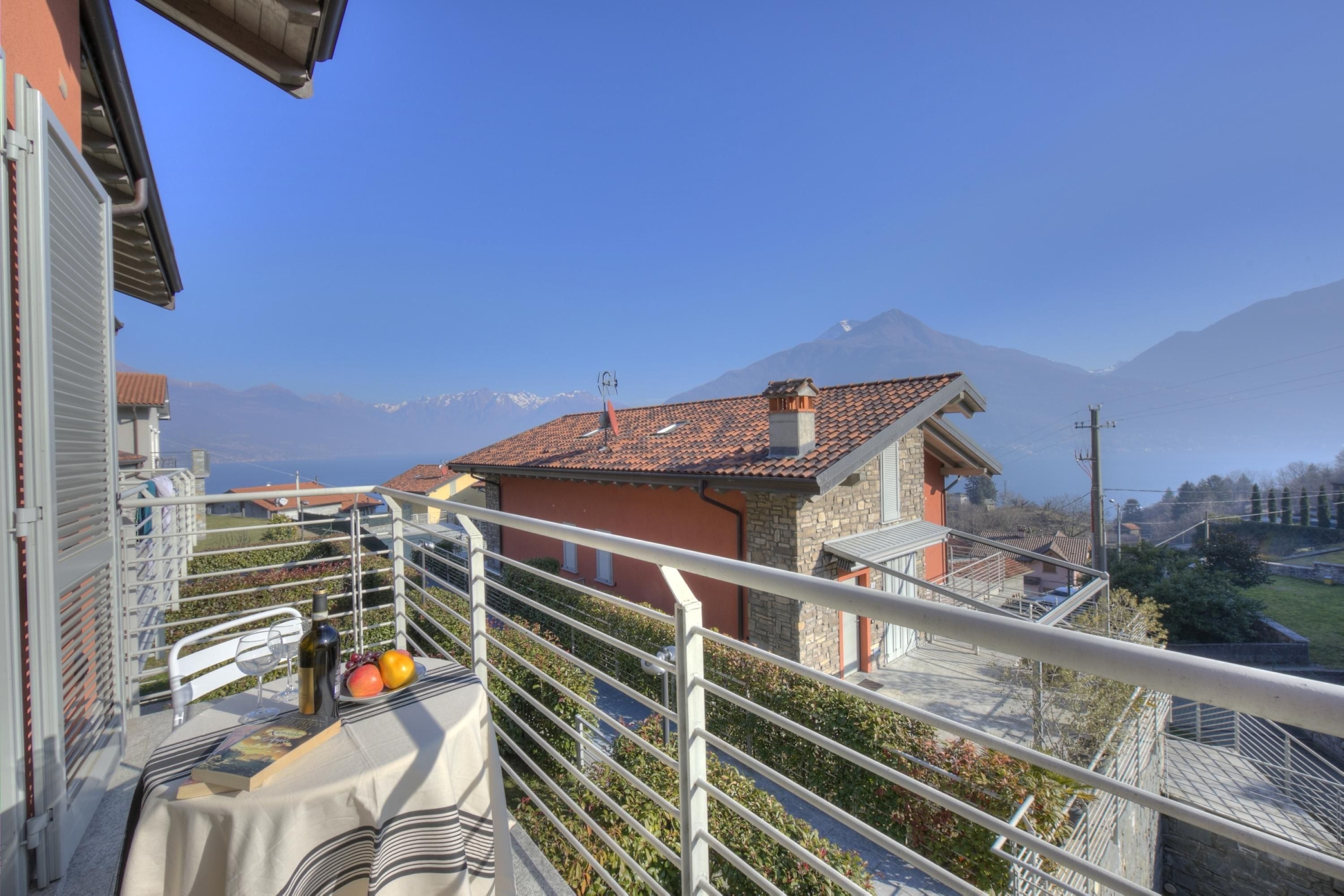 A balcony with a table set for two, overlooking a mountain landscape.