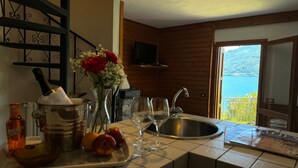 A kitchen with a sink, a stove, a vase with flowers, and a view of the sea. - Villetta Alessia in Menaggio (San Siro)