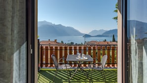 A balcony with a table and chairs, overlooking a lake and mountains. - CO RI Appartamenti 5 (Menaggio)