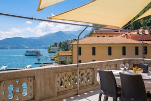 A terrace with a table set for dining, overlooking a lake with boats and buildings in the background. - Menaggio Tosca 3 in Menaggio (Menaggio)